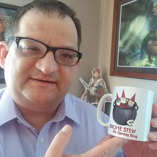 A man holds up a white gnome stew mug, showing off the logo.