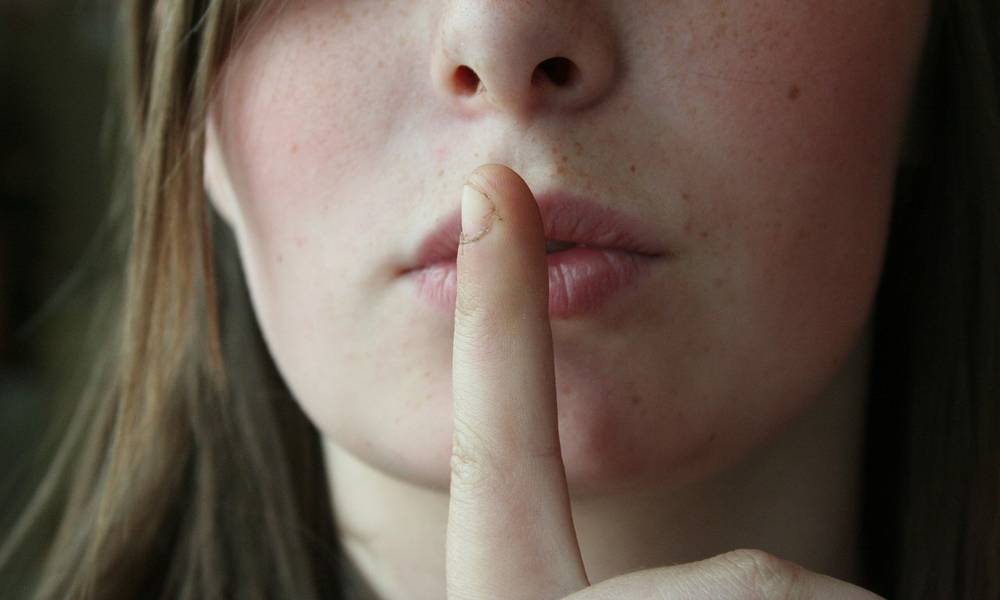 Close up of a woman holding a finger to her lips