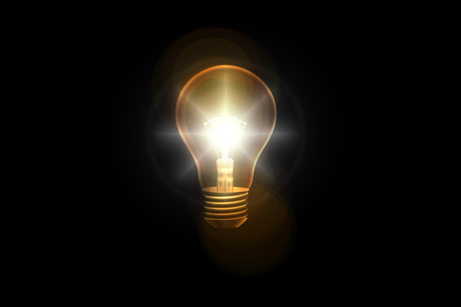 A incandescent light bulb lit against a black background.